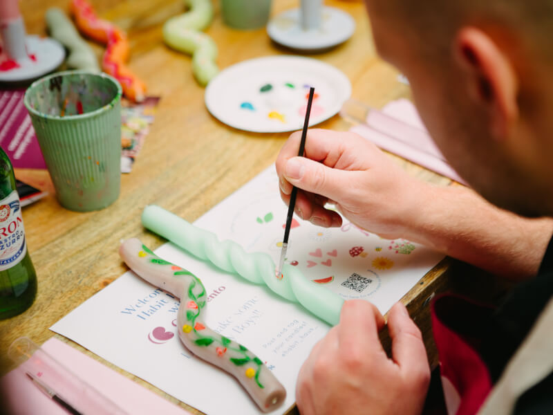 Man seen from behind painting a green candle stick